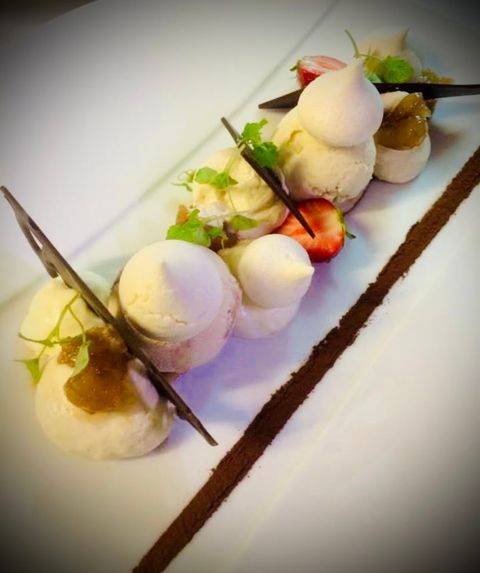 Meringues et quenelles glacées à la vanille, fraises et pointes de chocolat sur assiette longue