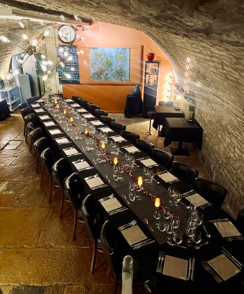 La cave voûtée en pierre, dressée d'une grande table pour un repas de groupe
