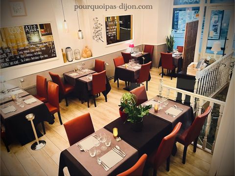 Tables dressées et fauteuils bordeaux dans la salle du restaurant