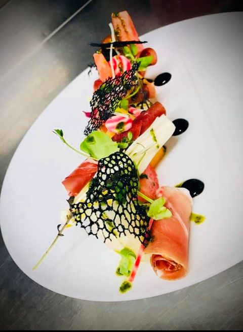 Roulades de jambon cru, tuiles dentelle noires et gouttes de balsamique sur assiette longue